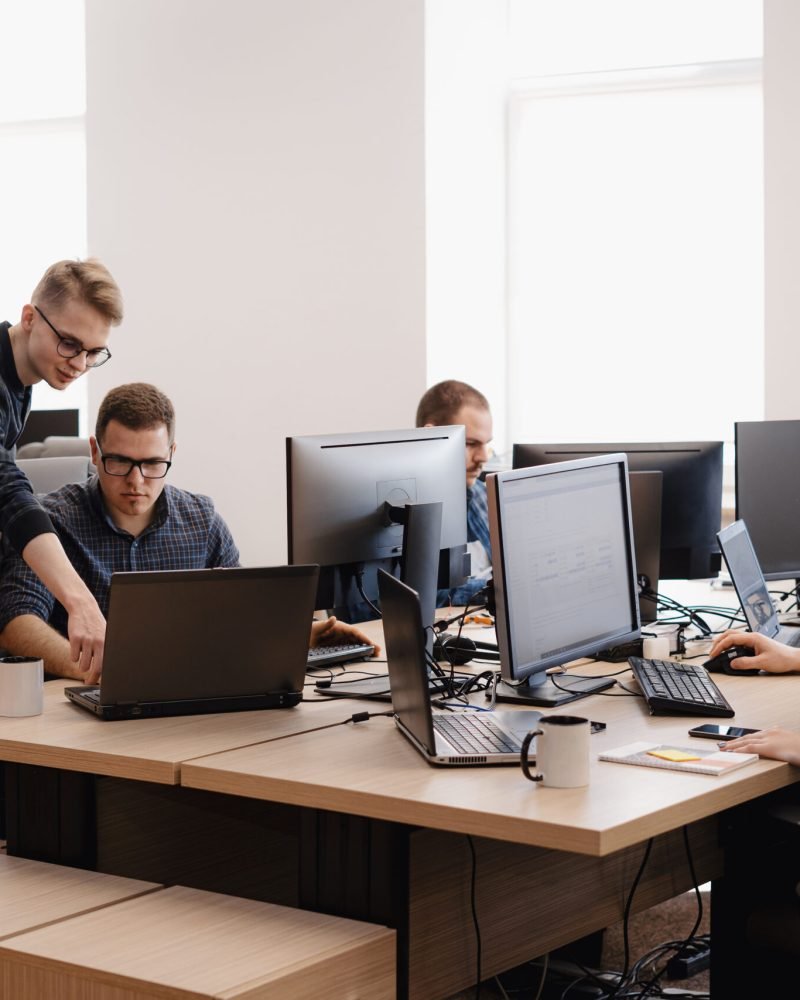 Full concentration at work. Group of young business people working and communicating while sitting at the office desk together with colleagues sitting in the background